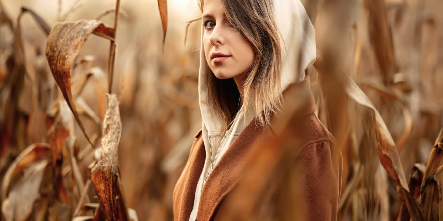 Style woman in coat on corn field in autumn time season