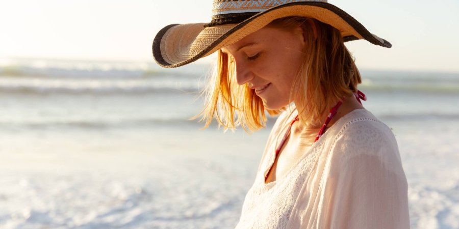 Woman wearing hat smiling on the beach